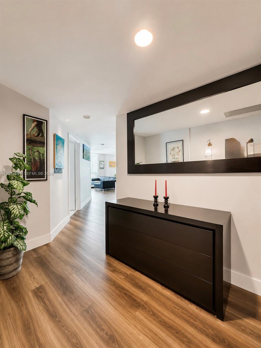 A hallway features wood-look flooring, a dark console table, a large mirror, and wall art — 55 SE 6th St # 2802, Miami FL 33131, MIAMI, FL