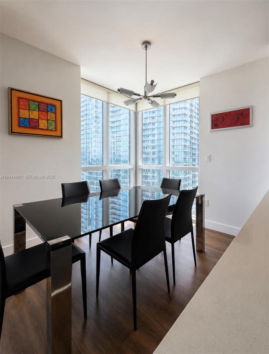 A dining room features a black glass table, six black chairs, and floor-to-ceiling windows — 55 SE 6th St # 2802, Miami FL 33131, MIAMI, FL
