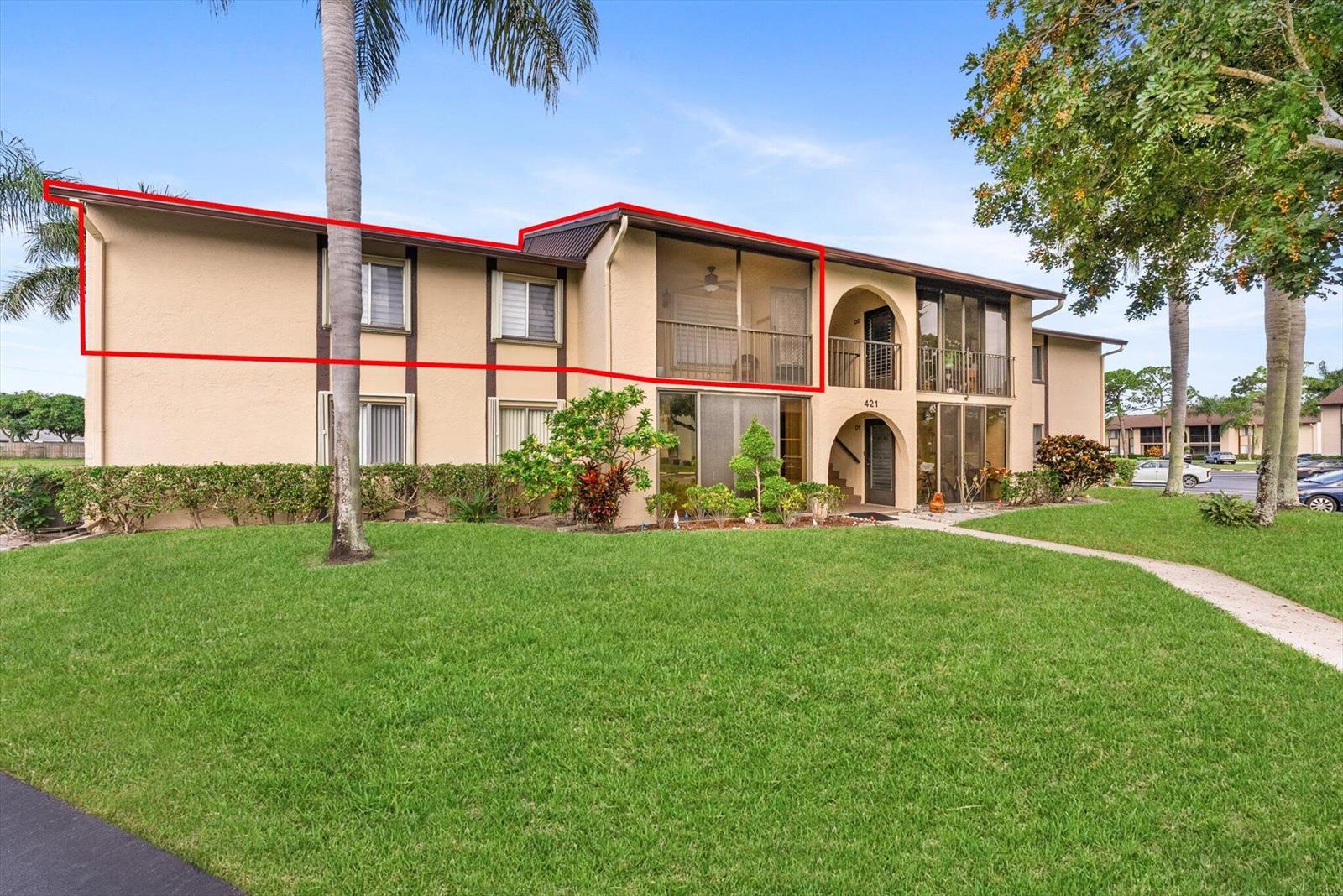 An exterior view of a two-story apartment building with a highlighted upper-level screened balcony — 421 Pine Glen Lane # A2, FL 33463, FL