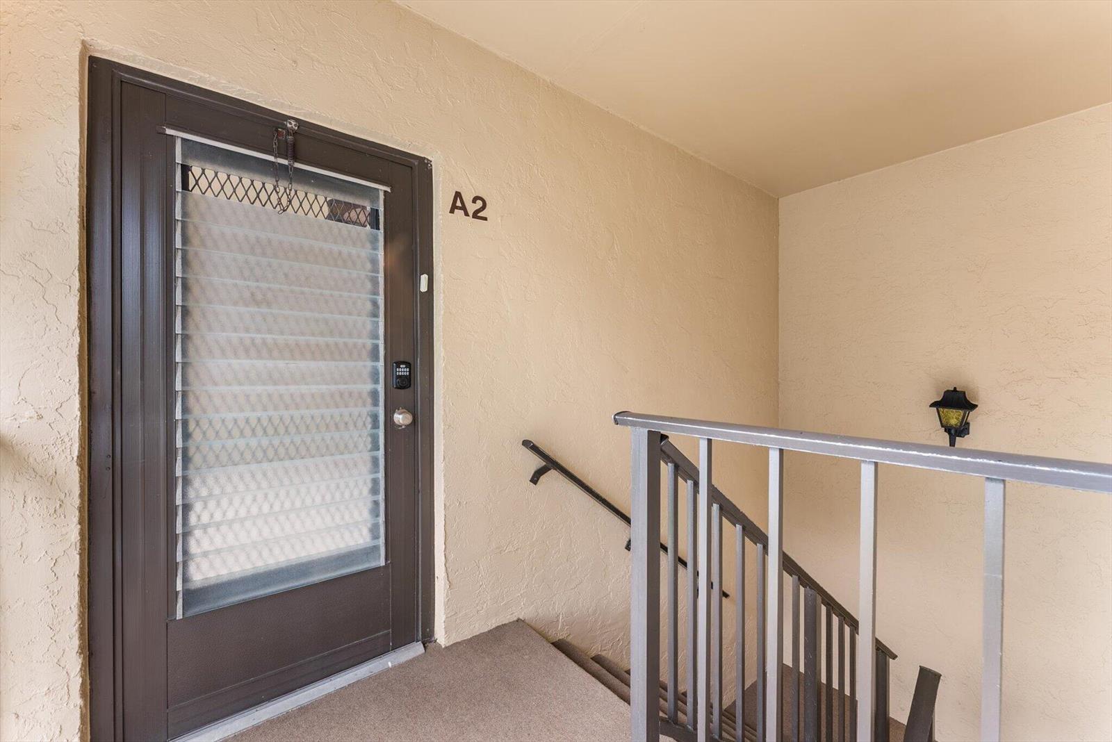 An exterior view of an apartment entrance door labeled A2 with a staircase and railing — 421 Pine Glen Lane # A2, FL 33463, FL
