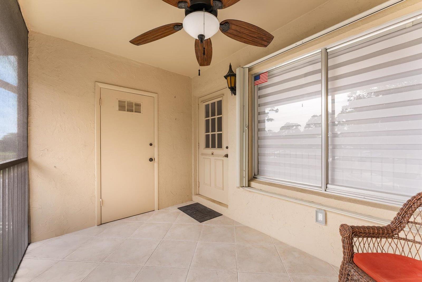 A covered patio features tiled flooring, a ceiling fan, two doors, and a large window — 421 Pine Glen Lane # A2, FL 33463, FL