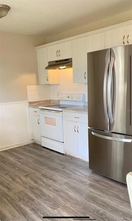 A kitchen features white cabinets, a stainless steel refrigerator, a white stove, and wood-look flooring — 2412 MARSHALL AVENUE, SANFORD, FL