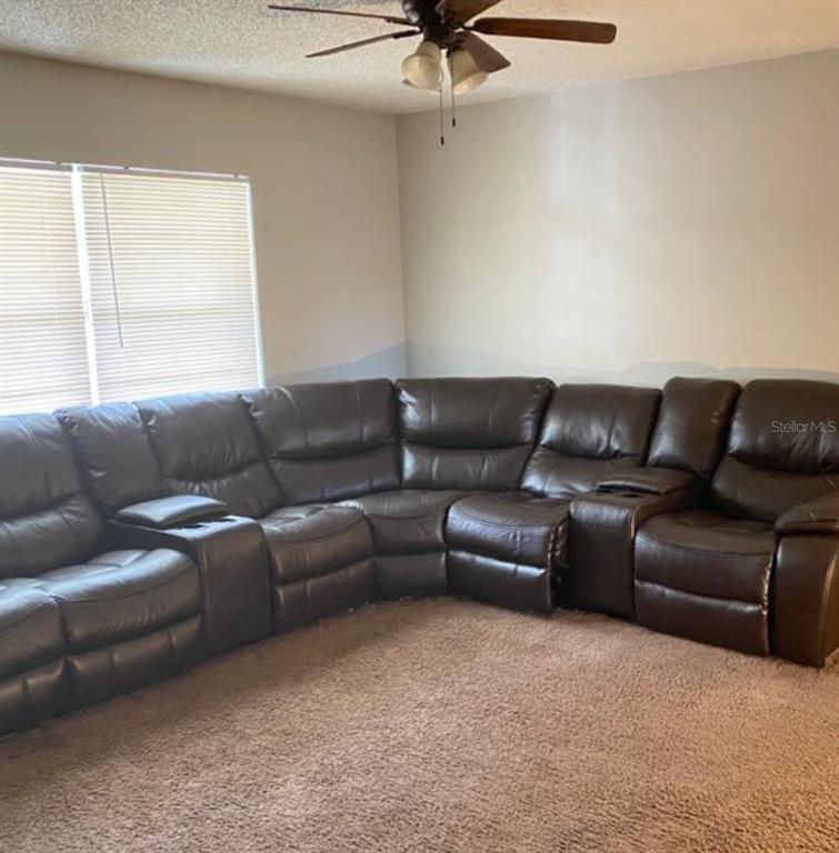 A living room features a large brown leather sectional sofa on beige carpet — 2412 MARSHALL AVENUE, SANFORD, FL
