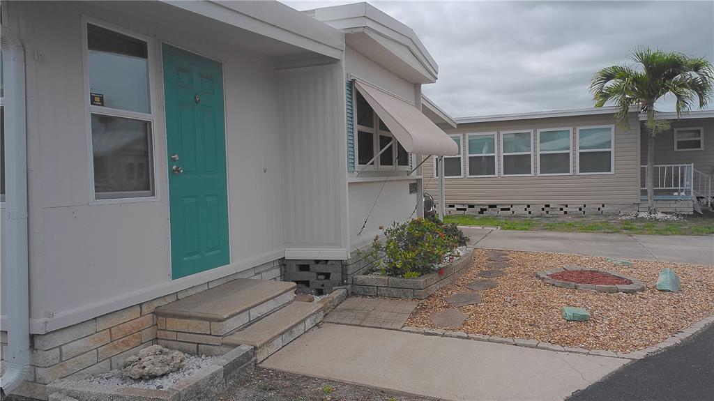 A mobile home exterior features a concrete driveway, a covered carport, and a white door — 7234 MOUNT FAIRFIELD ROAD NE UNIT 529, ST PETERSBURG, FL