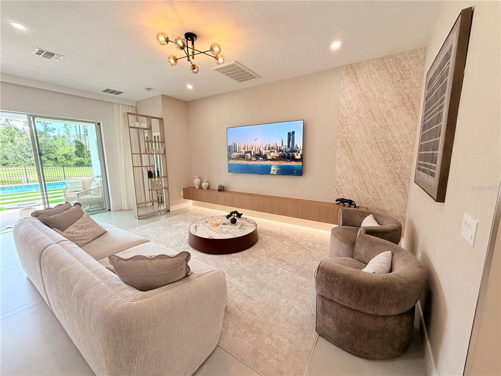 A bright entryway features a wooden console table, a glass-railed staircase, and a modern chandelier — 12676 SALOMON COVE DRIVE, WINDERMERE, FL