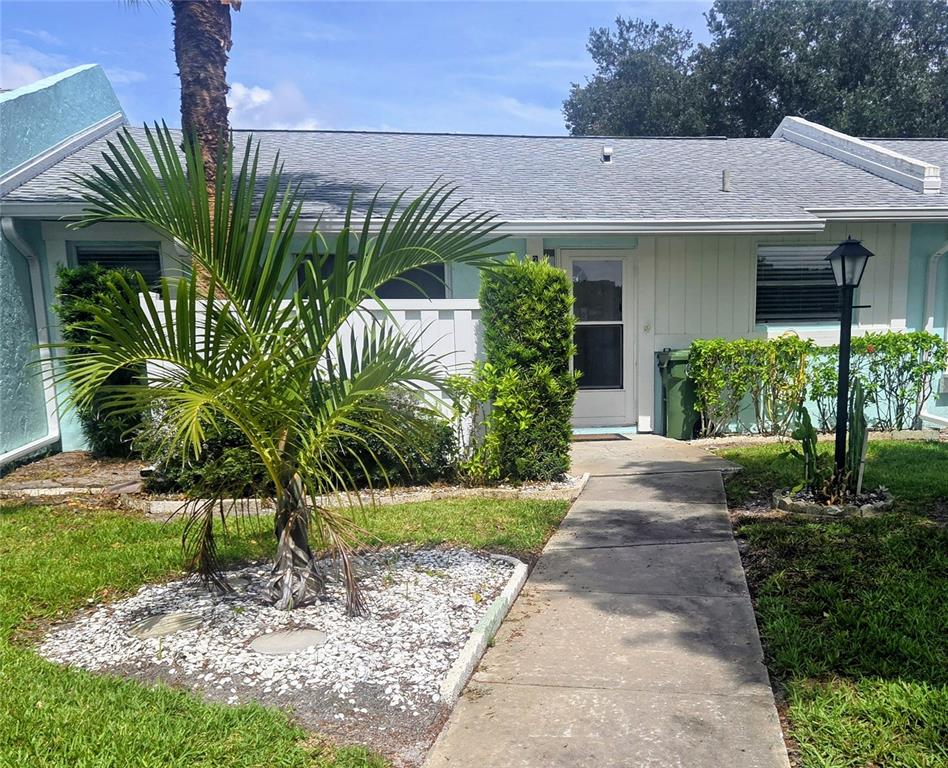 A walkway leads to the front entrance of a single-story home with a palm tree — 3603 41ST STREET W UNIT 3603, BRADENTON, FL