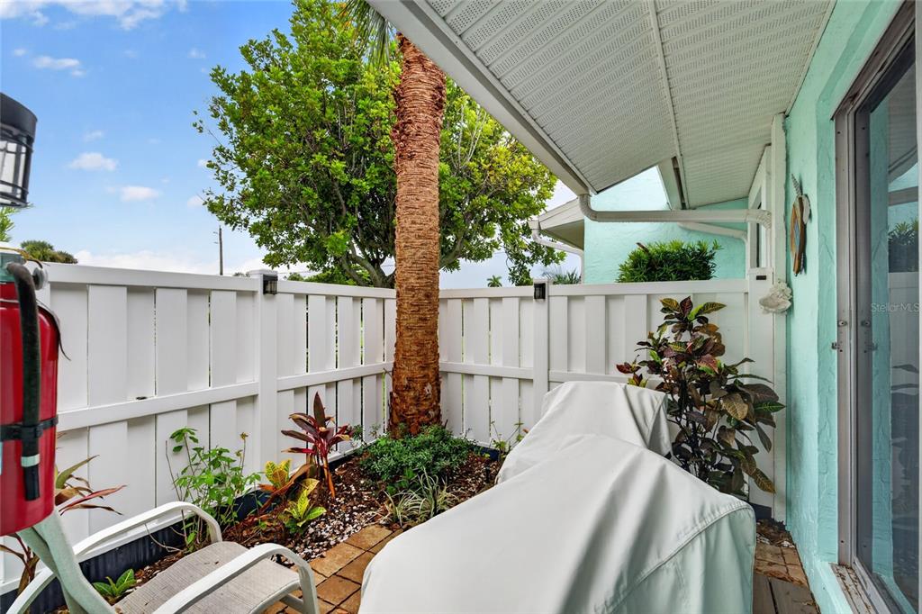 A covered patio features a white privacy fence, a palm tree, and outdoor furniture — 3603 41ST STREET W UNIT 3603, BRADENTON, FL