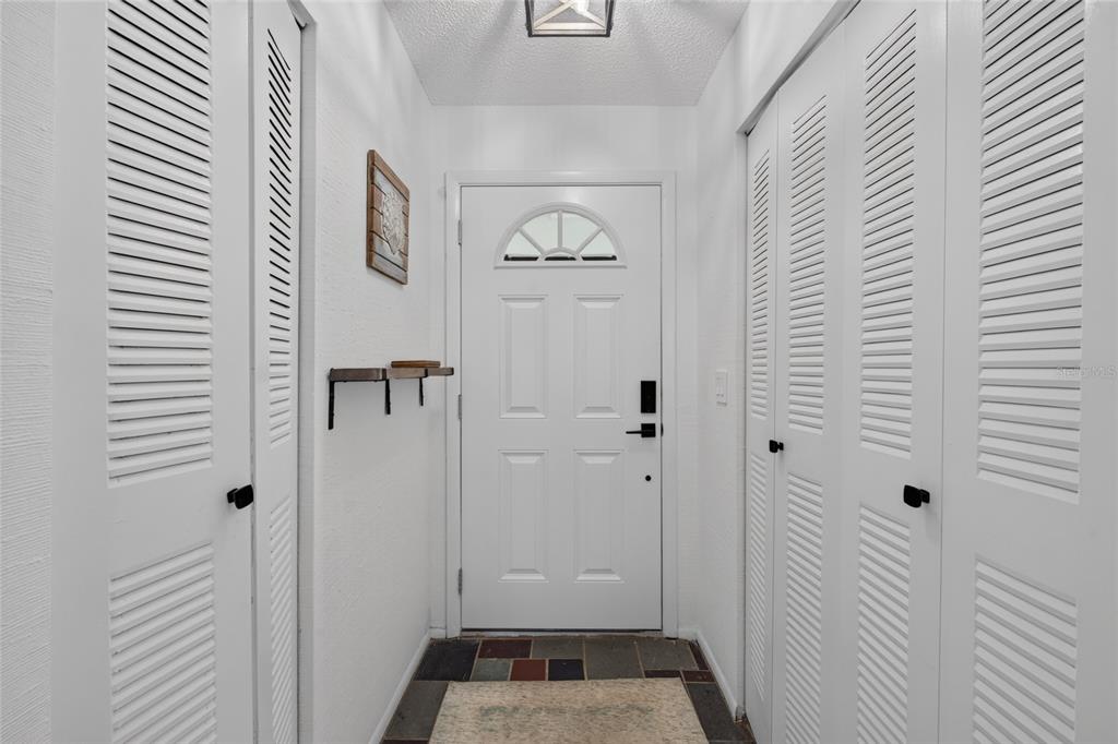 A white front door is centered between two sets of white louvered closet doors — 3603 41ST STREET W UNIT 3603, BRADENTON, FL