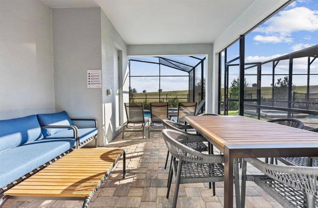 A covered patio features a dining set, outdoor sofa, and a screened-in pool area — 9144 DRIFTWOOD PATH, KISSIMMEE, FL