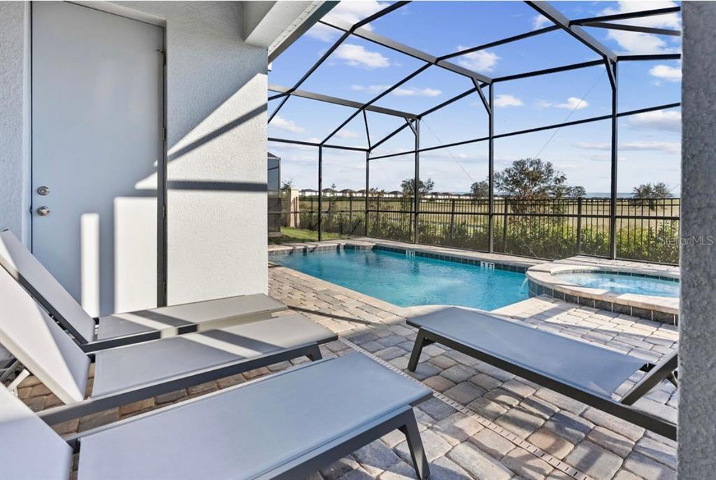 A screened-in patio features a swimming pool, a hot tub, and lounge chairs — 9144 DRIFTWOOD PATH, KISSIMMEE, FL