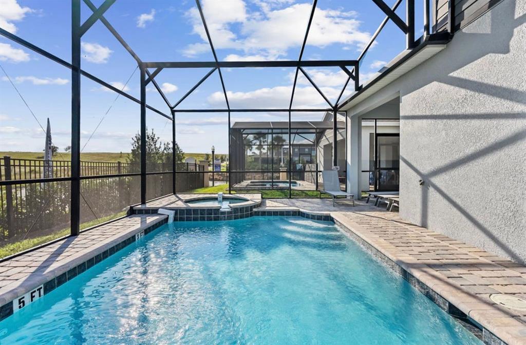A screened-in swimming pool and hot tub sit on a patio beside a house — 9144 DRIFTWOOD PATH, KISSIMMEE, FL