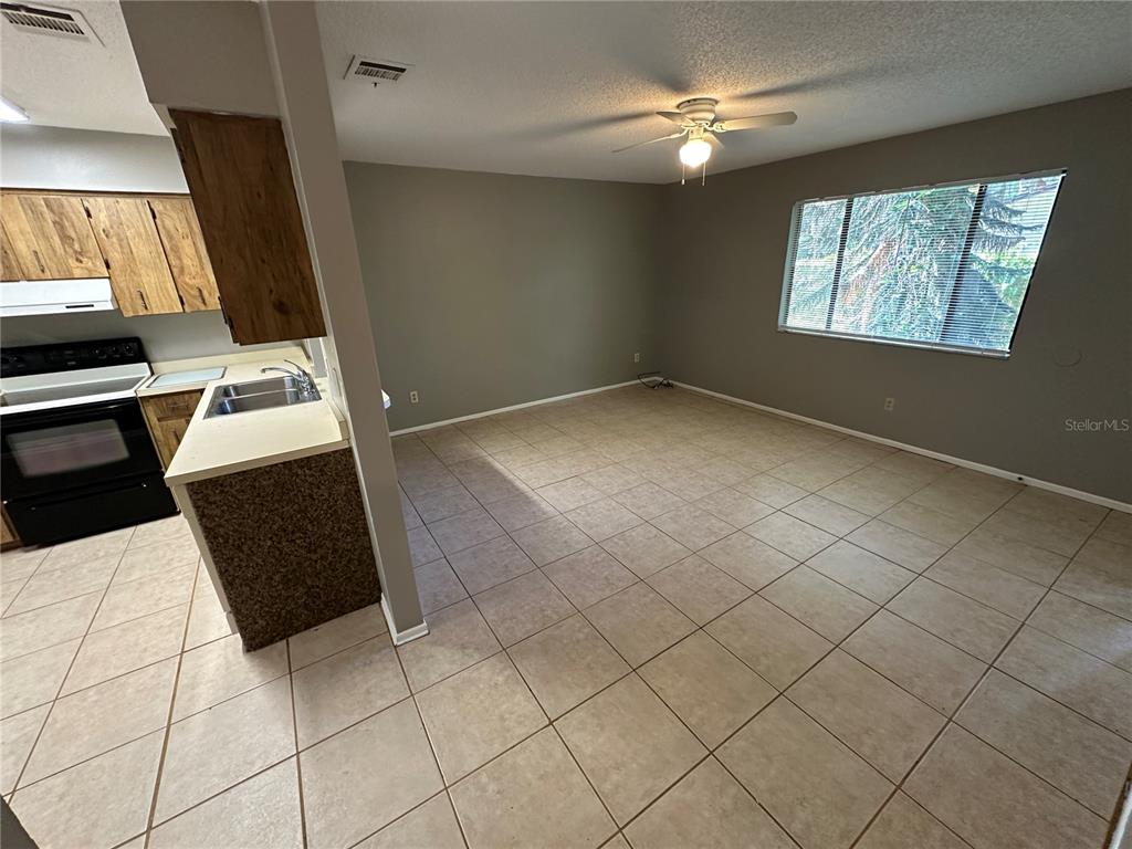 An open-concept kitchen and living area features tile flooring, gray walls, and a ceiling fan — 1916 WIZARD COURT, LONGWOOD, FL
