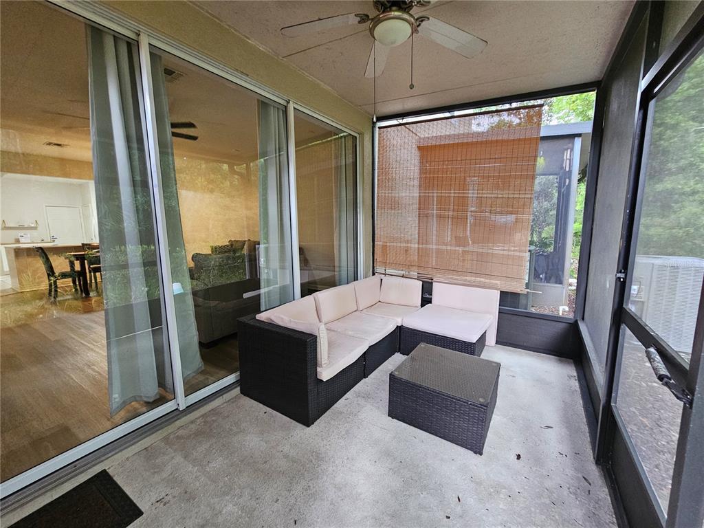 A screened-in patio features a dark wicker sectional sofa, a matching coffee table, and sliding glass doors — 5166 HAWKSTONE DRIVE, SANFORD, FL