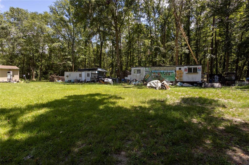 A grassy lot features three mobile homes situated in front of a dense forest — 18864 N HIGHWAY 329, MICANOPY, FL