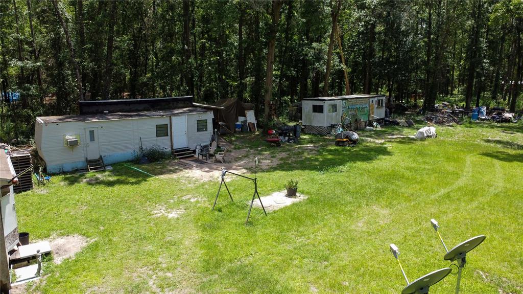 An aerial view shows two mobile homes situated on a grassy lot near a forest — 18864 N HIGHWAY 329, MICANOPY, FL