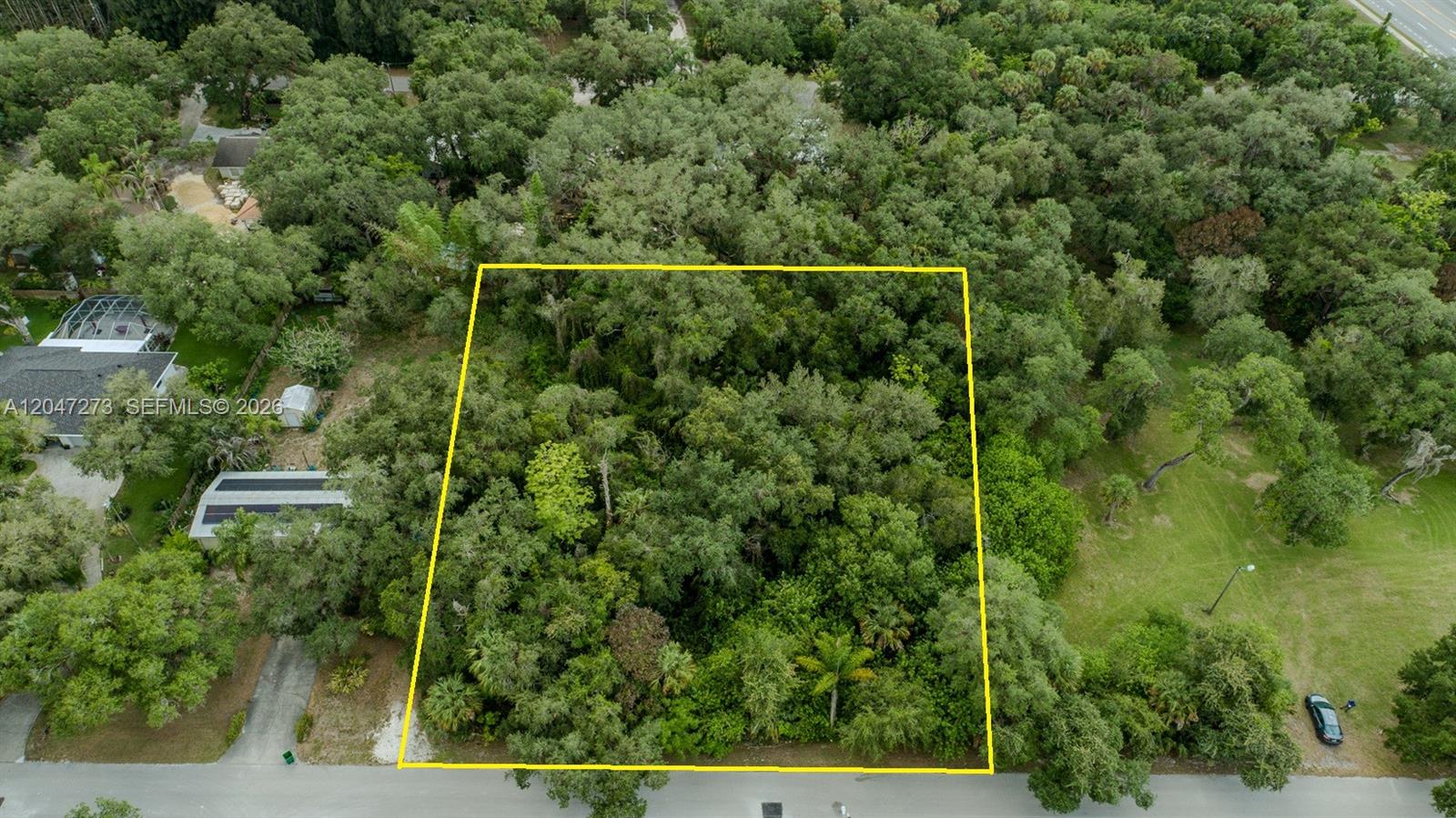 An aerial view shows a rectangular, tree-covered vacant lot outlined in yellow along a road — 543 E Hickpochee Ave, La Belle FL 33935, LA BELLE, FL