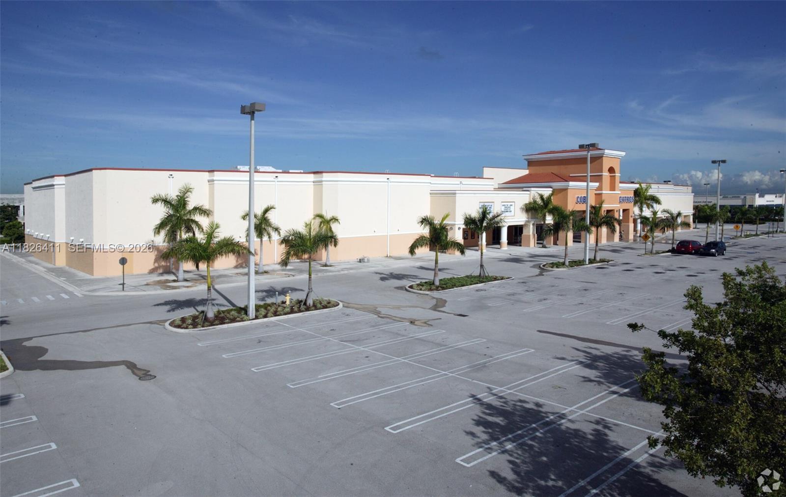An exterior view of a commercial building with a large parking lot and palm trees — 17355 NW 59th Ave, Hialeah FL 33015, HIALEAH, FL
