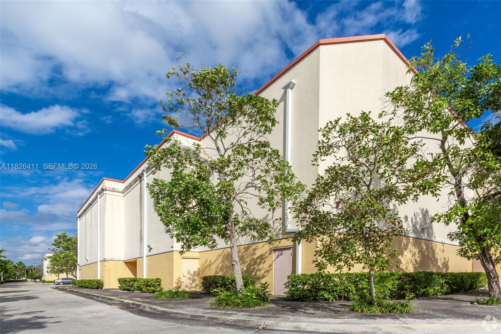 The exterior of a multi-story commercial building features beige stucco walls and a paved driveway — 17355 NW 59th Ave, Hialeah FL 33015, HIALEAH, FL