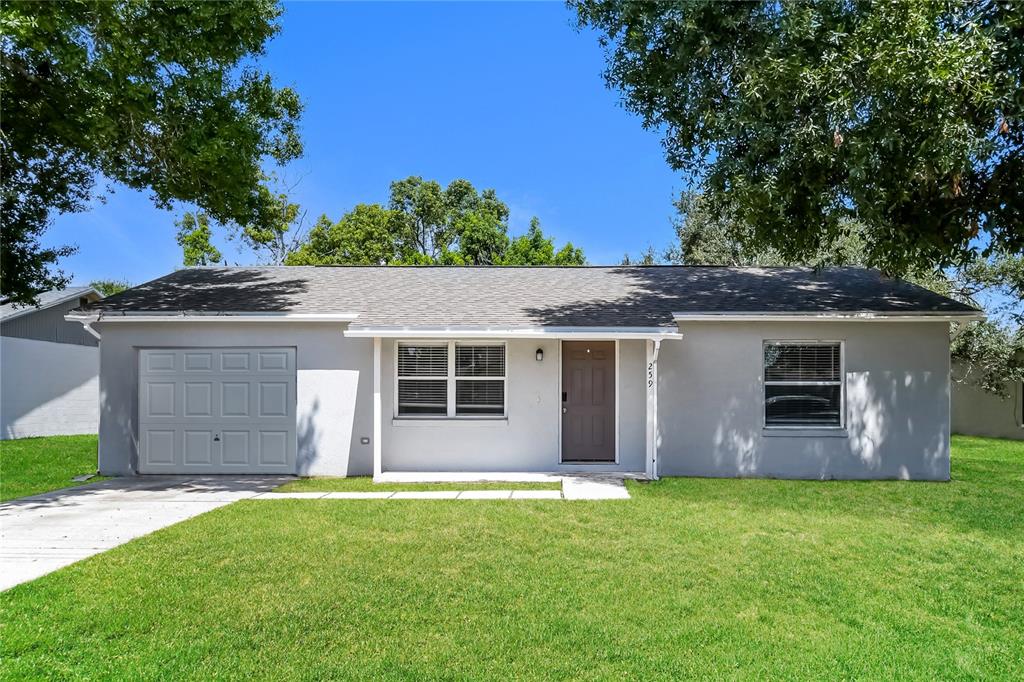 A single-story gray house with a one-car garage, a brown front door, and a lawn — 259 MAGELLAN DRIVE, KISSIMMEE, FL
