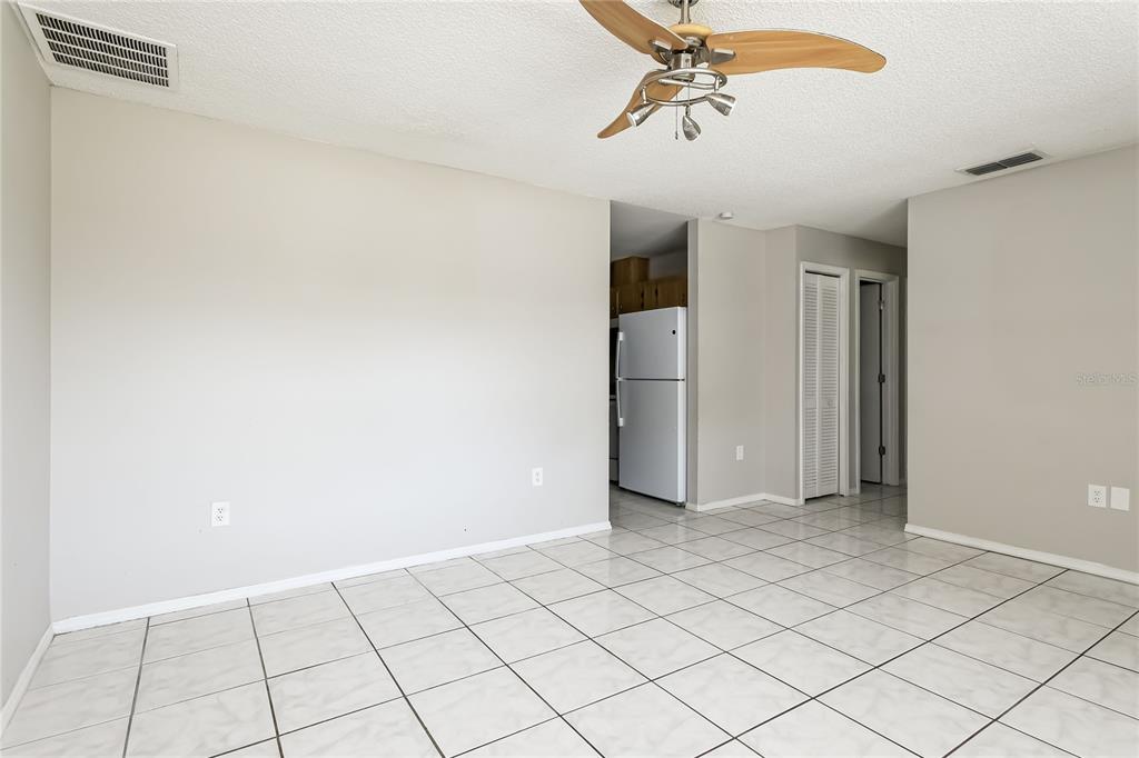 A room with light-colored tile flooring, a ceiling fan, and a view into a kitchen — 259 MAGELLAN DRIVE, KISSIMMEE, FL