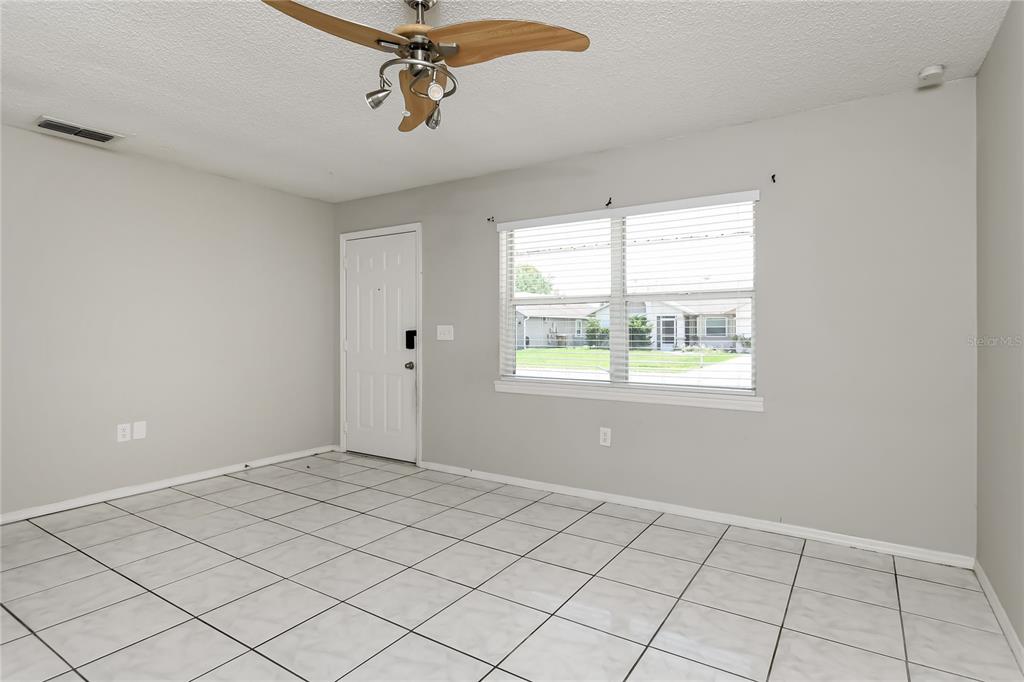 A room with light gray walls, white tile flooring, a ceiling fan, and a window — 259 MAGELLAN DRIVE, KISSIMMEE, FL