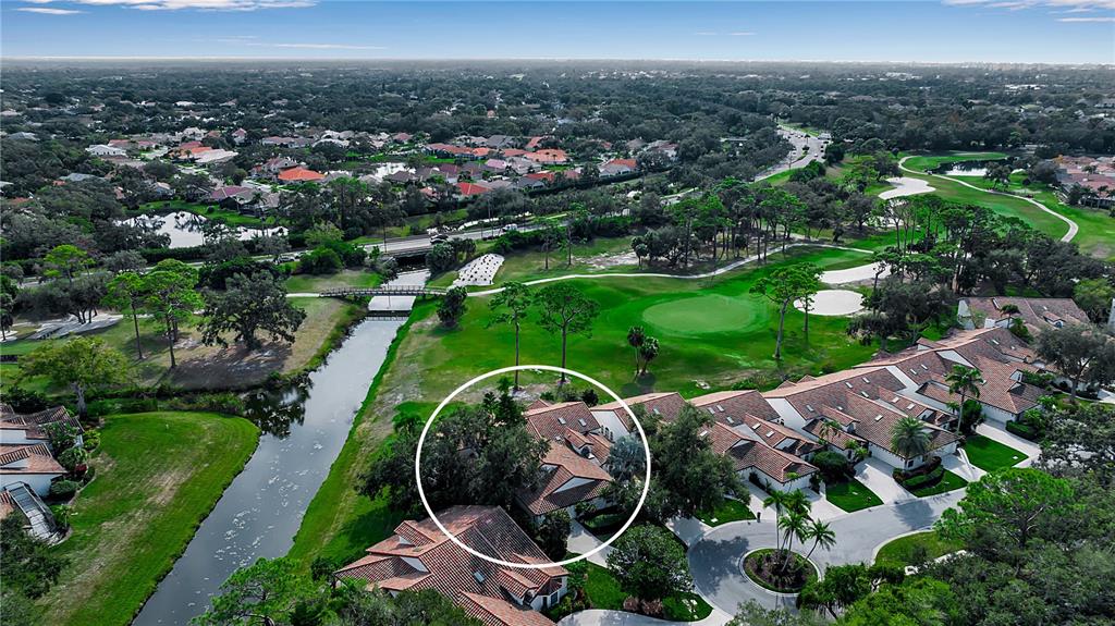 An aerial view shows a residential complex with tile roofs situated beside a golf course — 4360 CAMINO MADERA, SARASOTA, FL