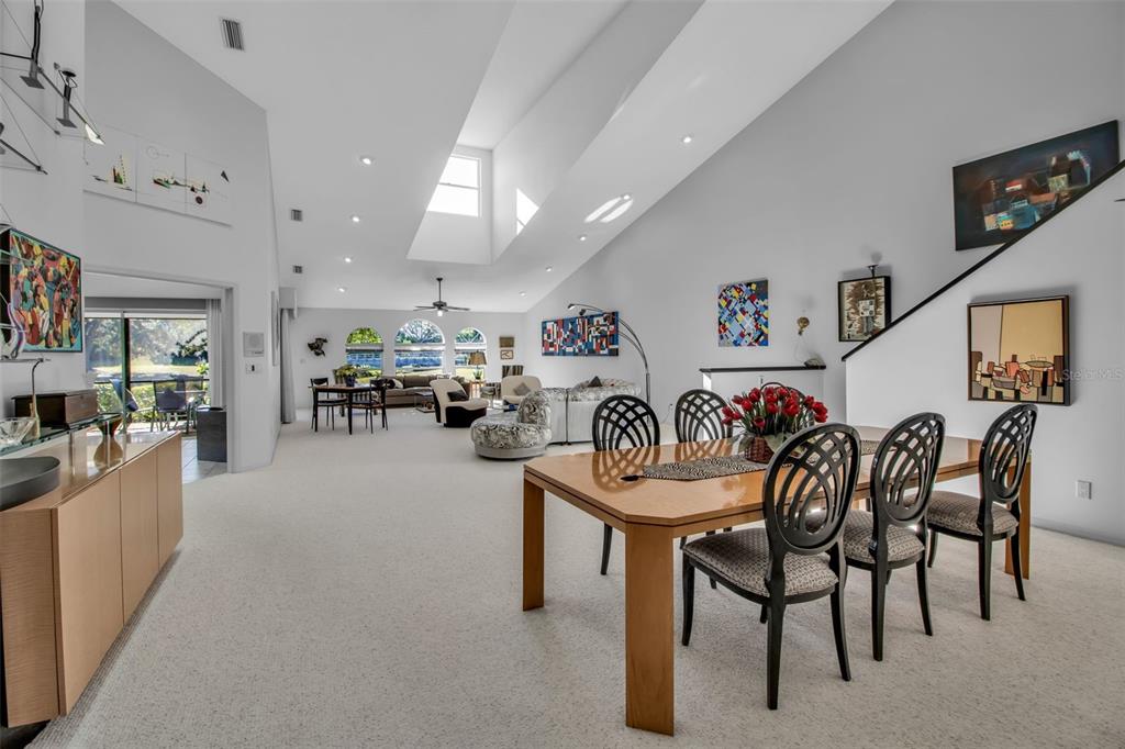 A spacious living and dining area with high vaulted ceilings, skylights, and wall-to-wall carpeting — 4360 CAMINO MADERA, SARASOTA, FL