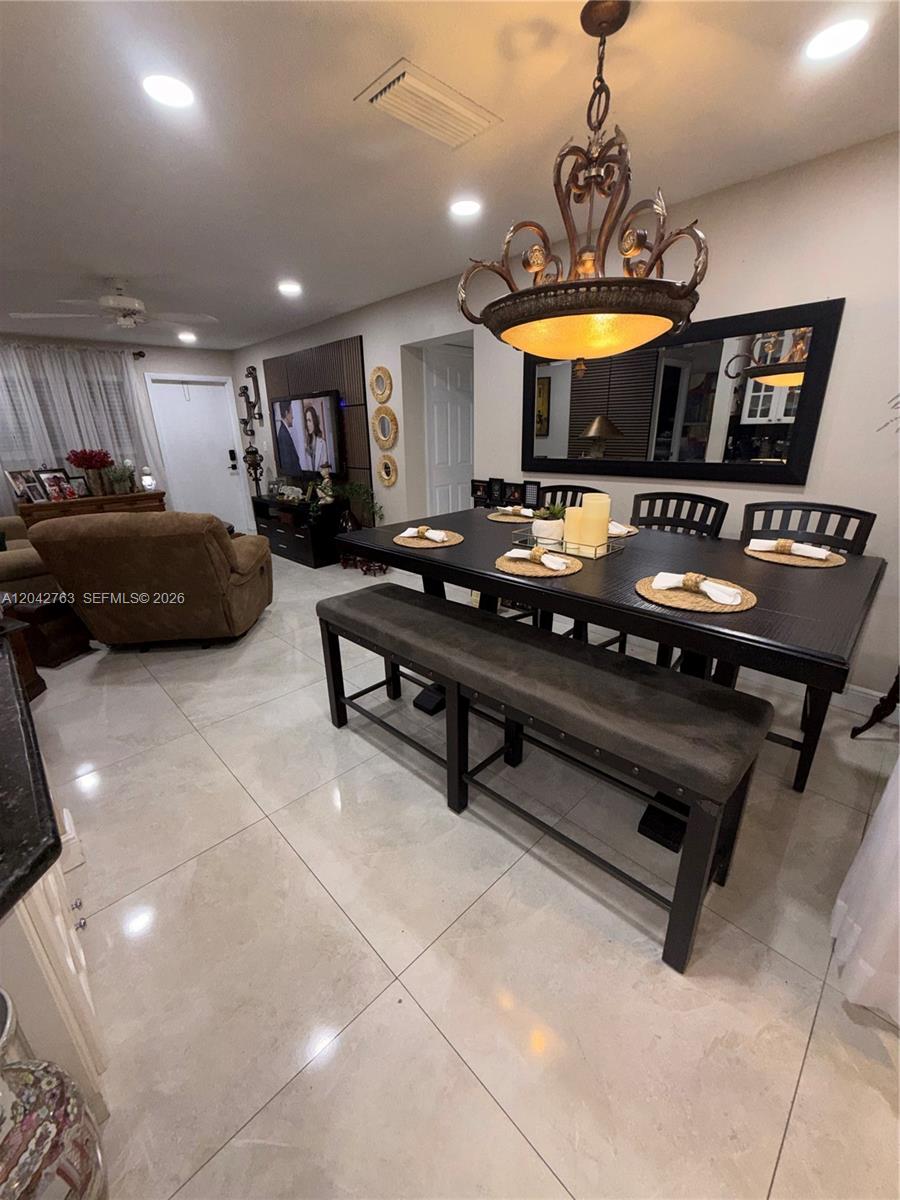 A dining area with a dark table, bench, and chairs sits beside a living room — 4100 Crystal Lake Dr # 111, Deerfield Beach FL 33064, DEERFIELD BEACH, FL