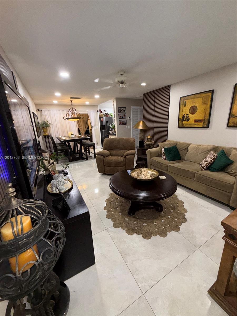 A living room features light tile floors, a brown sofa, and a round coffee table — 4100 Crystal Lake Dr # 111, Deerfield Beach FL 33064, DEERFIELD BEACH, FL