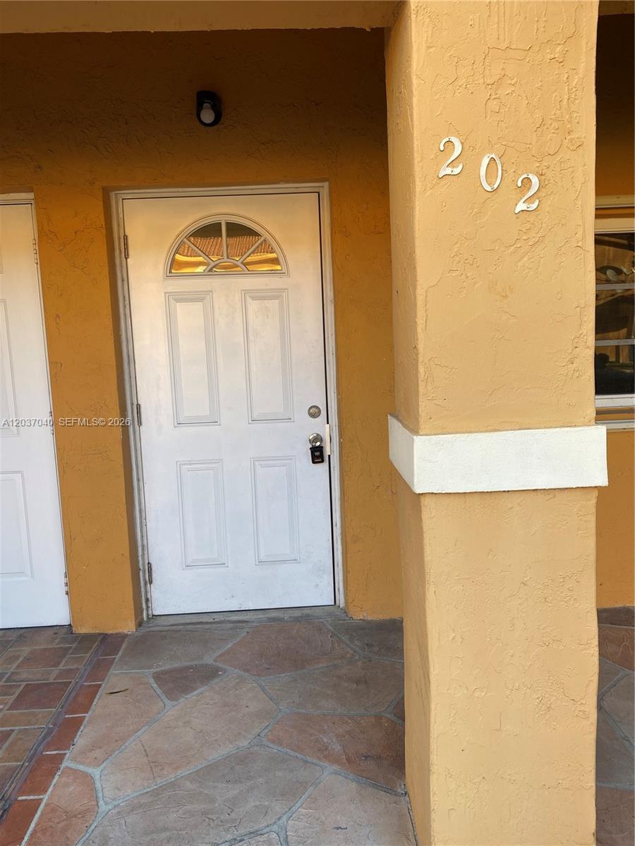 A white front door with a small arched window is set into a yellow wall — 3566 W 80th St # 57, Hialeah FL 33018, HIALEAH, FL