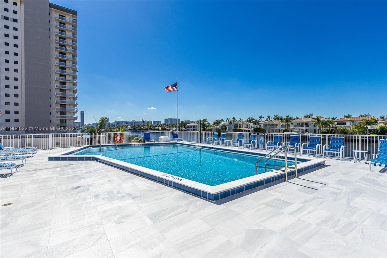 An outdoor swimming pool with blue lounge chairs sits on a tiled deck overlooking water — 1410 S Ocean Dr # 1702, Hollywood FL 33019, HOLLYWOOD, FL