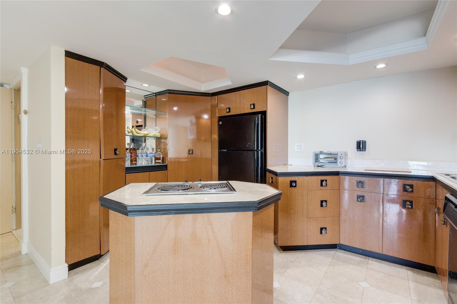 A kitchen features light wood cabinets with black trim, a central island cooktop, and tile flooring — 1410 S Ocean Dr # 1702, Hollywood FL 33019, HOLLYWOOD, FL