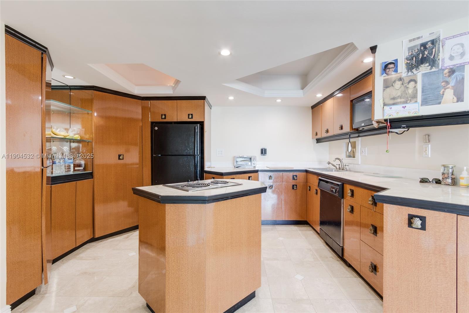 A kitchen features light wood cabinetry, black appliances, a central island, and tiled flooring — 1410 S Ocean Dr # 1702, Hollywood FL 33019, HOLLYWOOD, FL