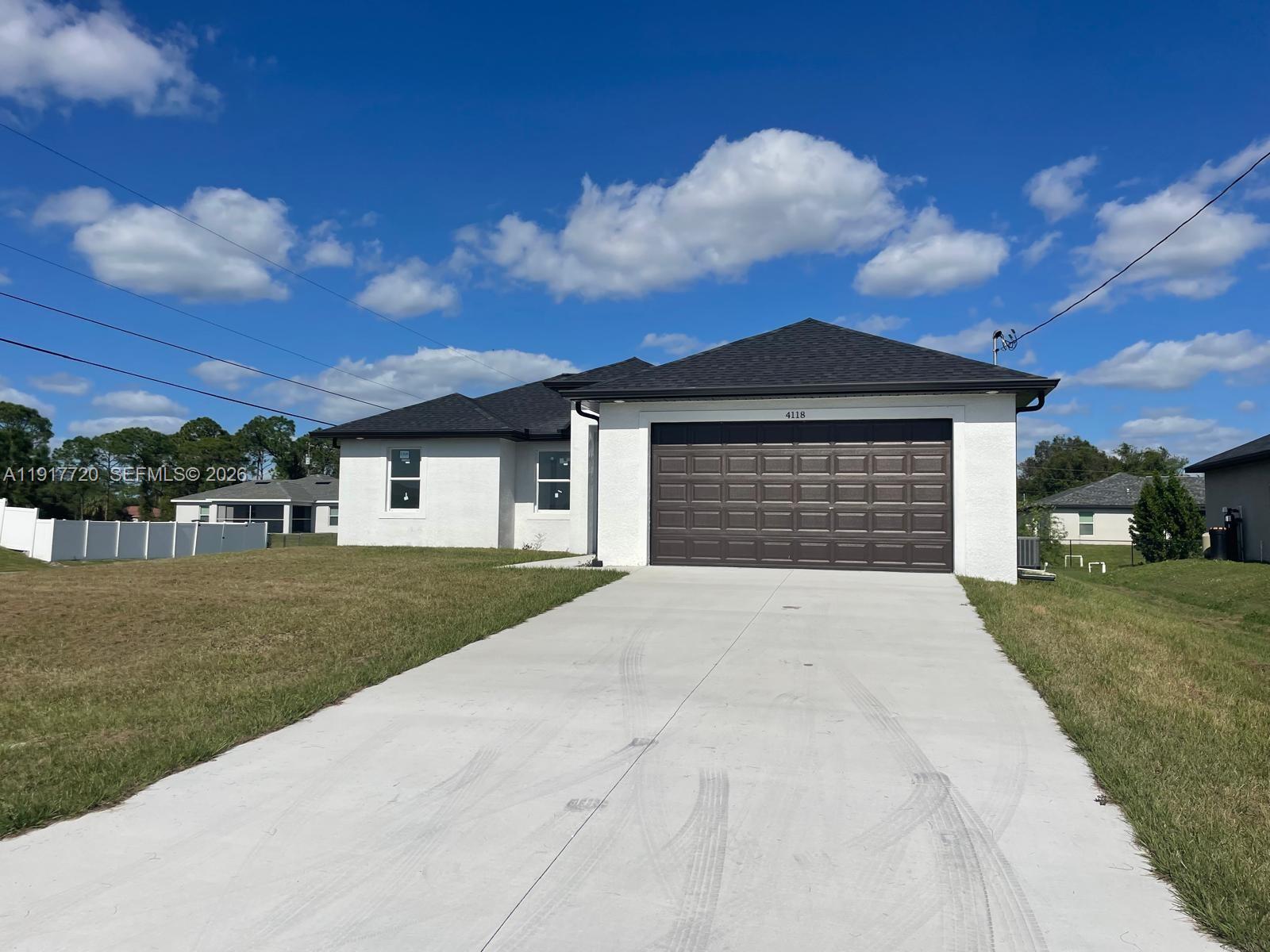 A single-story white house with a dark roof and a two-car garage — 4118 4th ST SW, Lehigh Acres FL 33976, LEHIGH ACRES, FL