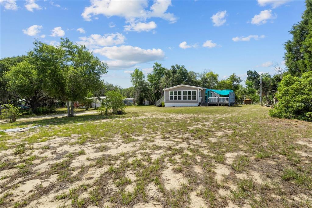 A single-story manufactured home sits on a large, sandy lot with scattered trees — 2742 MASTERPIECE ROAD, LAKE WALES, FL