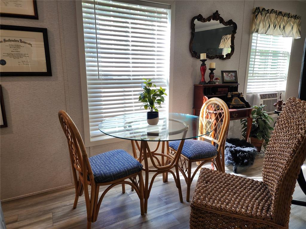 A dining area features a glass-topped rattan table, two matching chairs, and a decorative mirror — 4150 S SPANIEL TRAIL, INVERNESS, FL