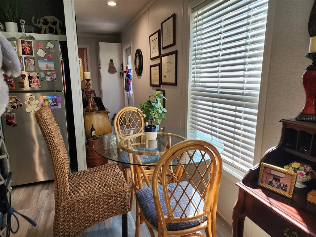 A dining area features a glass-topped table with rattan chairs near a window and refrigerator — 4150 S SPANIEL TRAIL, INVERNESS, FL