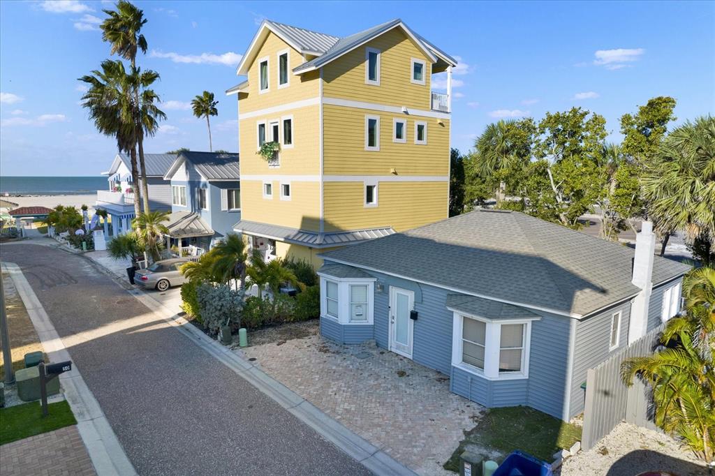 An aerial view shows a tall yellow house next to a single-story blue house — 39 181ST AVENUE W, REDINGTON SHORES, FL