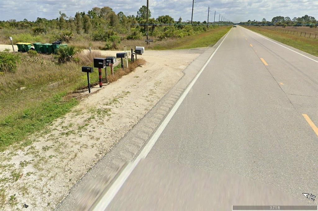 A row of mailboxes stands along the shoulder of a rural two-lane asphalt road — 50964 BERMONT ROAD, PUNTA GORDA, FL