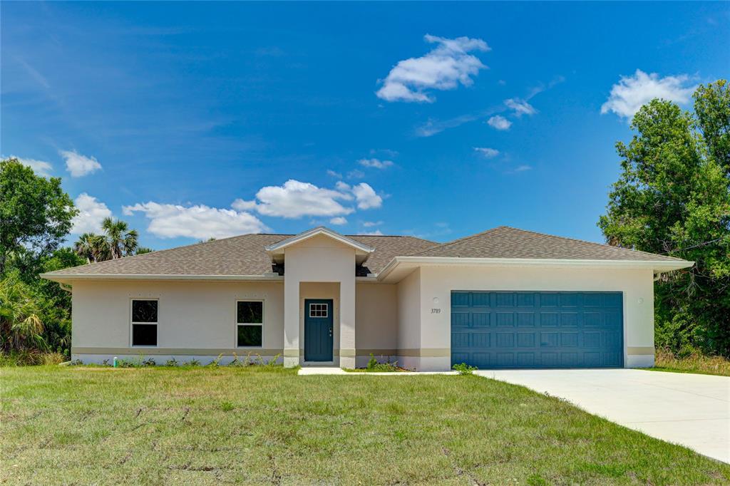 A single-story house with a blue front door, a two-car garage, and a grassy yard — 3789 URIAH STREET, NORTH PORT, FL