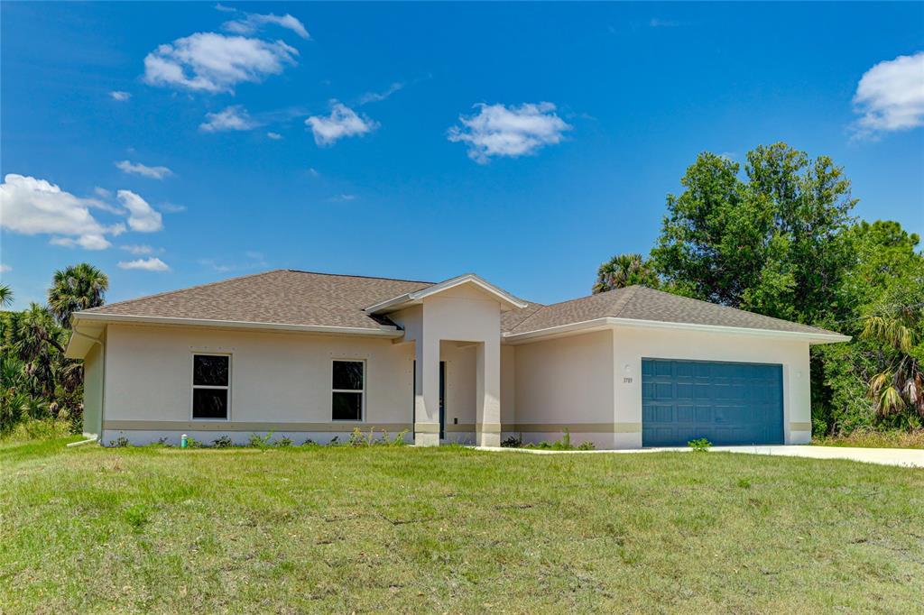 A single-story house with a tan exterior, a blue garage door, and a grassy lawn — 3789 URIAH STREET, NORTH PORT, FL