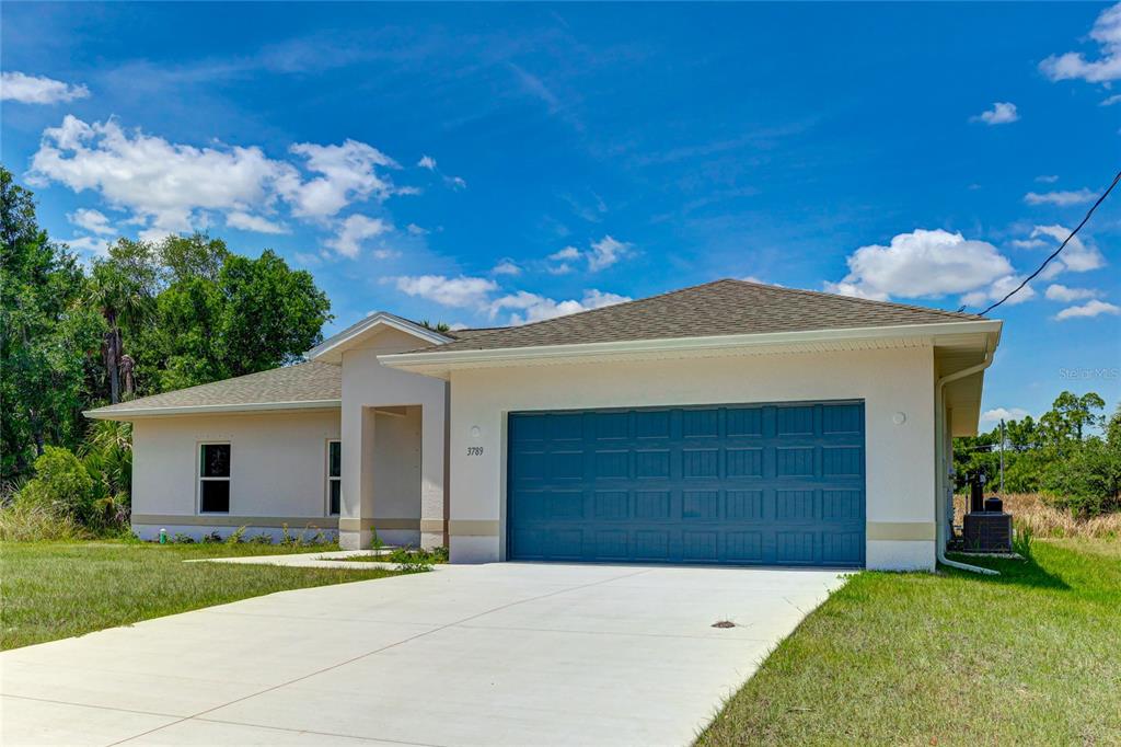 A single-story house with a blue garage door and a concrete driveway under a blue sky — 3789 URIAH STREET, NORTH PORT, FL