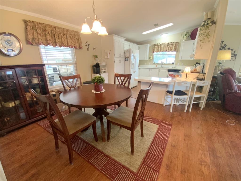 A dining area with a round wooden table sits adjacent to an open-concept kitchen — 4842 SE 130TH PLACE, BELLEVIEW, FL