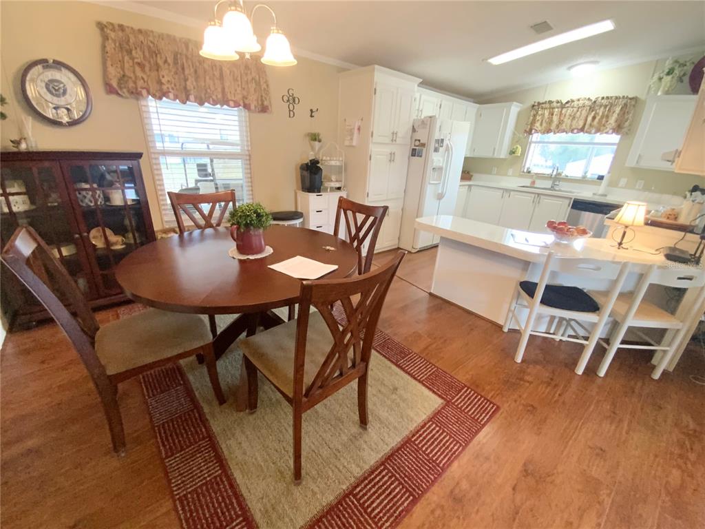 A dining area with a round wooden table sits adjacent to a white kitchen — 4842 SE 130TH PLACE, BELLEVIEW, FL