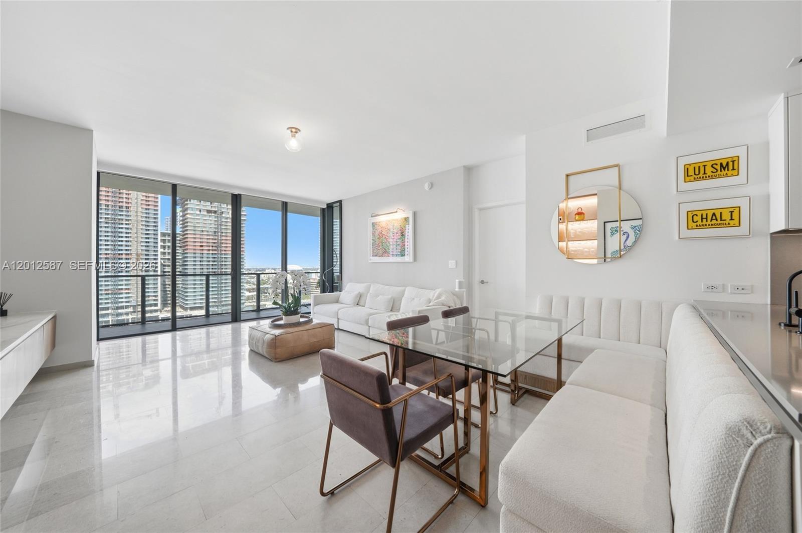 A modern living and dining area with white furniture, a glass table, and floor-to-ceiling windows — 68 SE 6th St # 1904, Miami FL 33131, MIAMI, FL