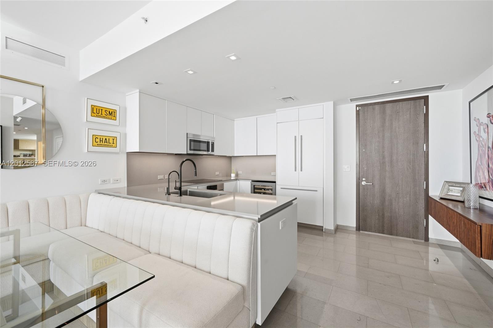 A modern kitchen features white cabinetry, stainless steel appliances, and a built-in dining banquette — 68 SE 6th St # 1904, Miami FL 33131, MIAMI, FL