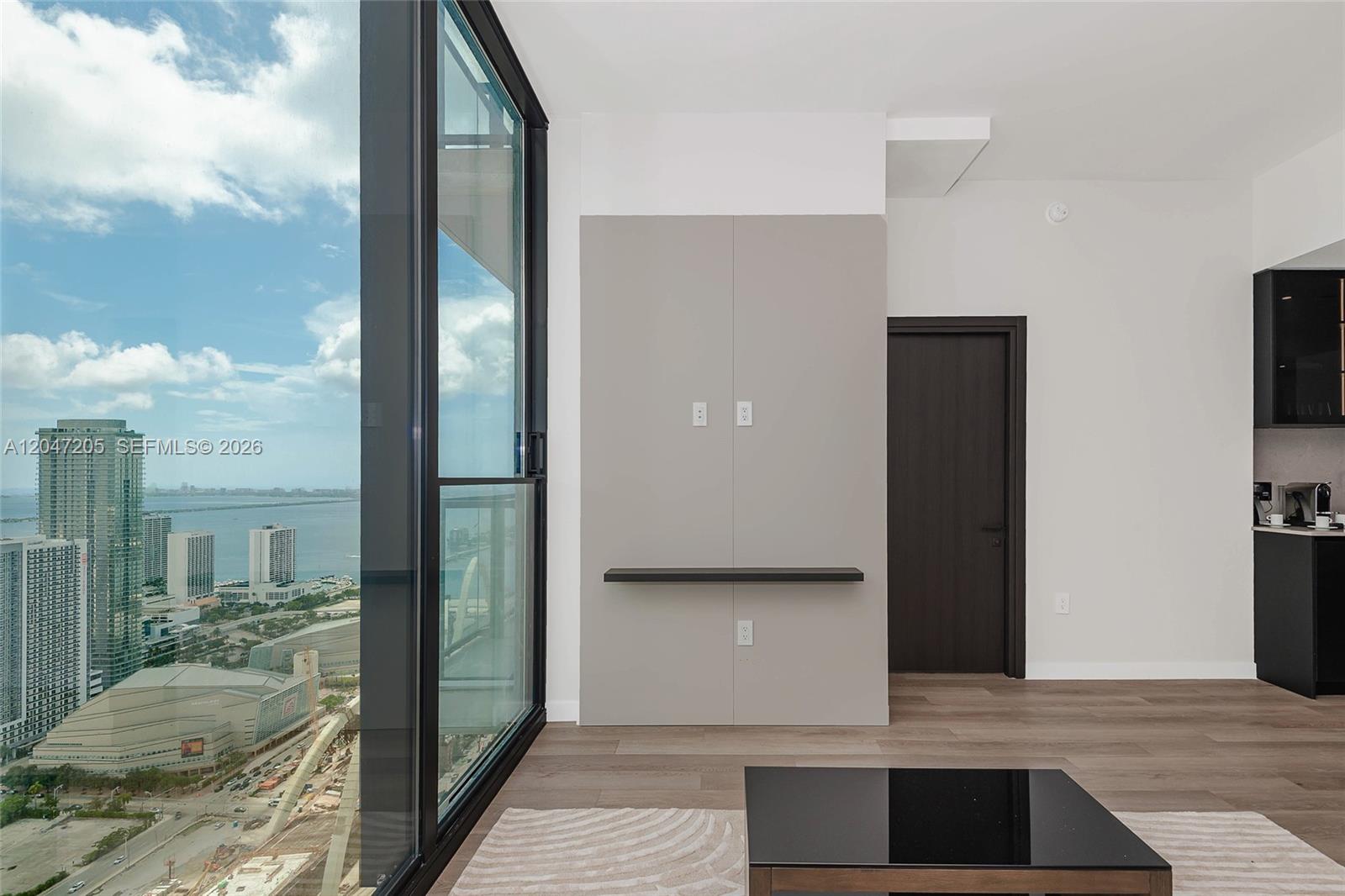 A modern living room features a floor-to-ceiling window with city and water views — 20 NE 11 ST # 4901, Miami FL 33132, MIAMI, FL