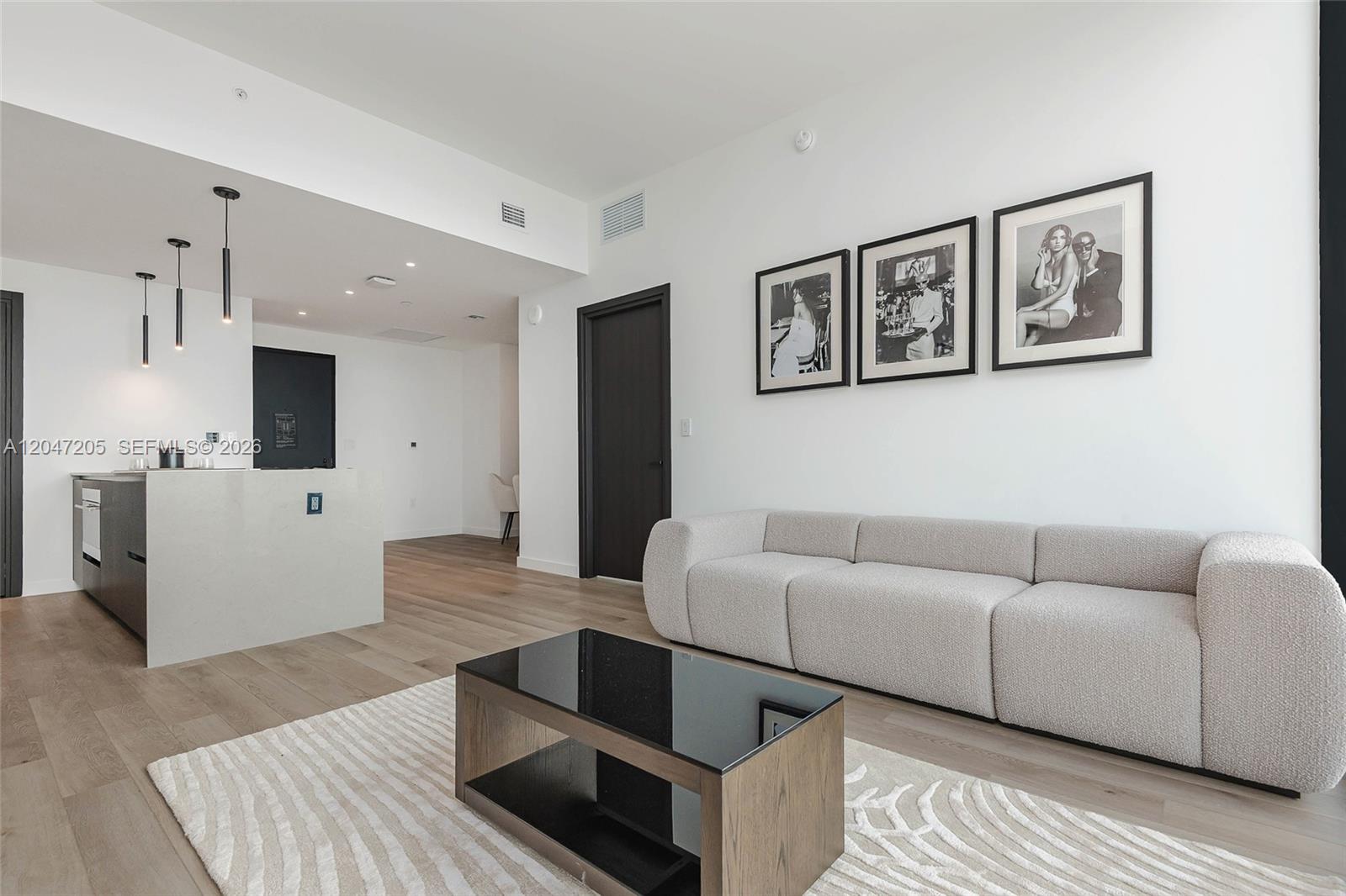 A modern living room features a light-colored sofa, a coffee table, and framed wall art — 20 NE 11 ST # 4901, Miami FL 33132, MIAMI, FL