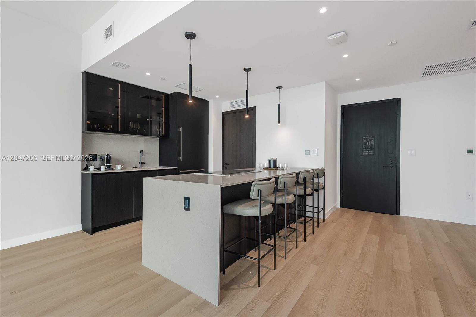 A modern kitchen features dark cabinetry, a stone-topped island with bar seating, and light flooring — 20 NE 11 ST # 4901, Miami FL 33132, MIAMI, FL