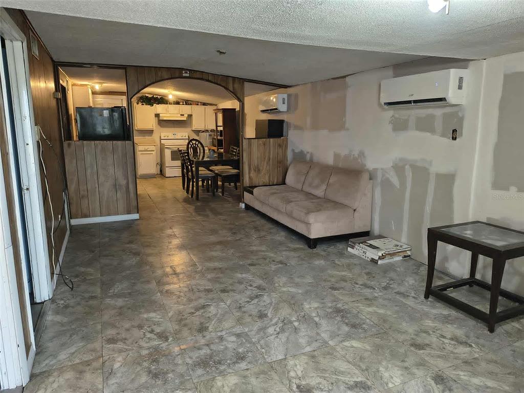 A living room with tile flooring, a beige sofa, and an arched entryway to a kitchen — 611 SHORT STREET, PLANT CITY, FL